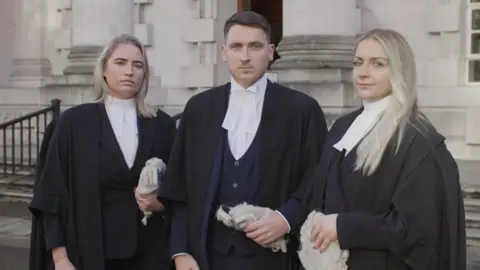 Ben Robinson/ Brown O'Connor Communications It shows barristers Aoife Marken, Thomas Thibodeau and Taryn Graham outside a courthouse