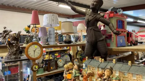 Shelves full of knick-knacks and small statues, clocks and lamps