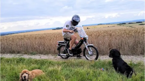 Paul Taylor/Moronic Moped Marathon Paul Taylor on his moped accompanied by his two dogs