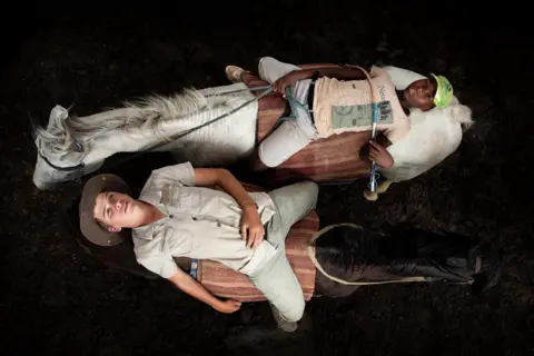 Coenraad Heinz Torlage Aerial view of two young people lying on the backs of horses