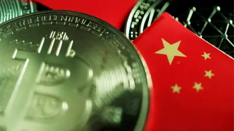 Reuters A real-world coin designed with the Bitcoin logo lies scattered on a table amid some miniature Chinese flags