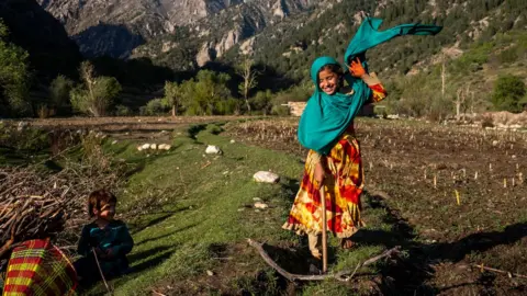 An 8-year-old chops wood with her family in Nuristan province