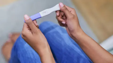 Getty Images A woman's hands holding a pregnancy test