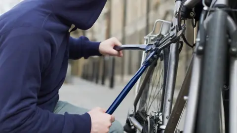 Getty Images A man wearing a hoodie stealing a bike