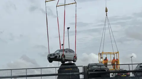 Kate Bradbrook/BBC cars being removed on a crane