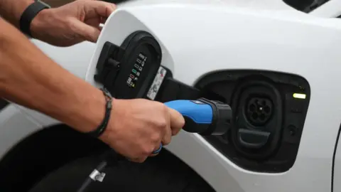 PA Media A man charges an electric car