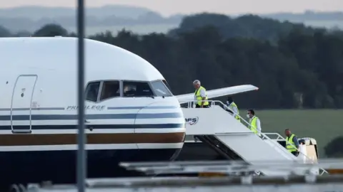 Reuters Members of the staff board a plane reported by British media to be first to transport migrants to Rwanda