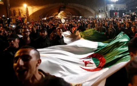 Ramzi Boudina/REUTERS People carry a national flag as they celebrate on the streets after Algeria"s President Abdelaziz Bouteflika has submitted his resignation, in Algiers, Algeria, 2 April 2019.