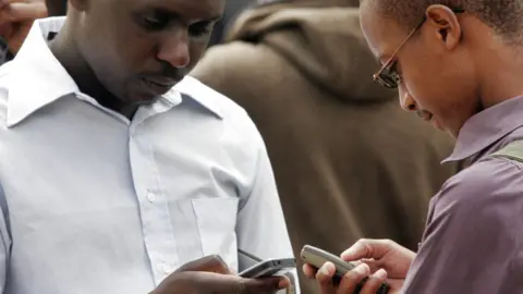 AFP Two Kenyans texting on their phones - archive shot