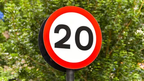 Ceri Breeze/Getty Road sign marking the start of a 20 mph speed limit zone in a residential area