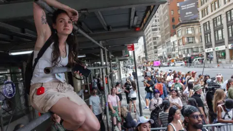 EPA A woman sits on scaffolding, while a crowd of onlookers gather below