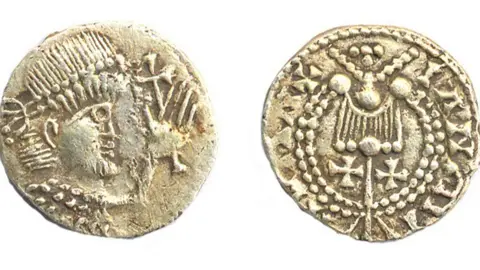 Adrian Marsden Two sides of a later Saxon gold coin. On the left is a close up of a man in profile, wearing a Roman-style diadem or headdress. His left hand is raised and behind it is a cross. On the right the coin has a lyre-shape above two crosses in the middle and a pattern of dots and symbols on the outside.