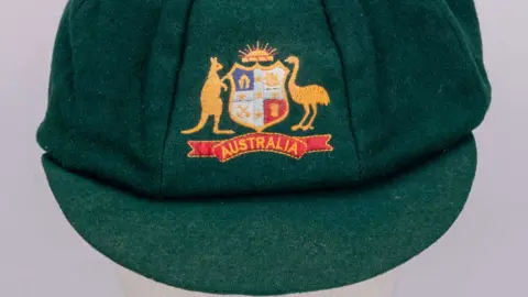 Budds Picture of a dark green cap worn by Geoff Marsh. The Australian coat of arms is stitched to the front, while the cap is made from a felt green.