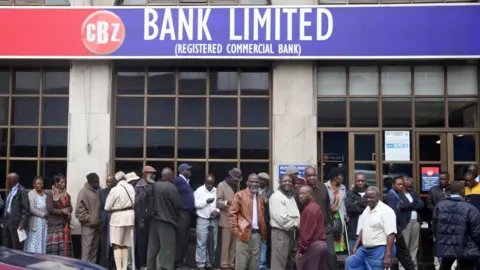 Reuters People queue to draw money outside a bank in Harare, Zimbabwe, 15 November 2017