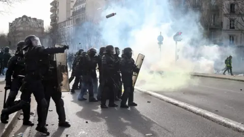 AFP Police officers throw tear gas to protesters during the 13th consecutive Saturday demonstration called by the "Yellow Vests"