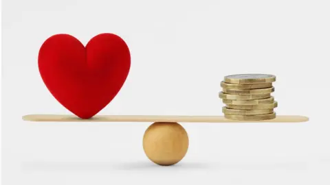 Getty Images Heart and money balancing
