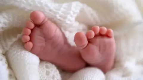 A close-up of the feet of a bay wrapped in a white blanket.