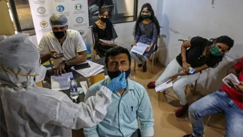 EPA A health worker collects a nasal swab sample of an employee of Justdial call centre, to conduct a Rapid Antigen test for COVID-19, at the Justdial head office in Mumbai, India, 09 October 2020.
