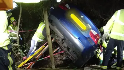 Fire crews work to stabilise a car