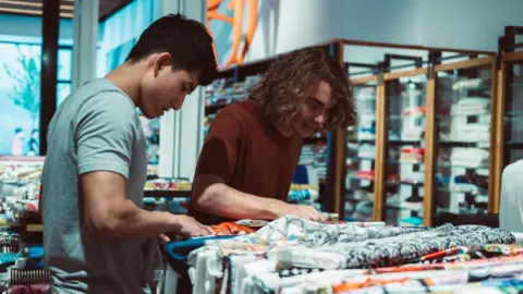 Getty Images Men browsing clothes in a shop