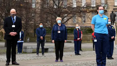 Getty Images Health workers stand outside the Glasgow Royal Infirmary and observe a minute's silence