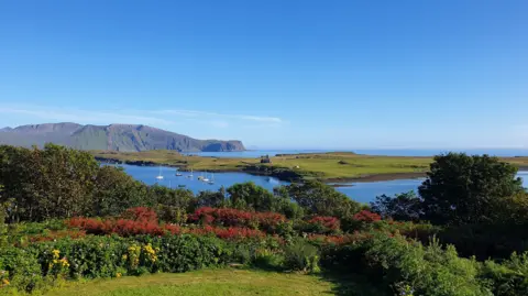 The National Trust for Scotland Landscape image of the Isle of Canna on a sunny day with clear blue skies,  looking out to the sea