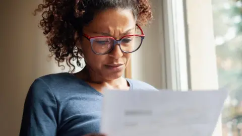 Getty Images Woman looking at bill