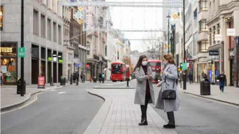 PA Media Two people stand in the middle of an empty Oxford Street