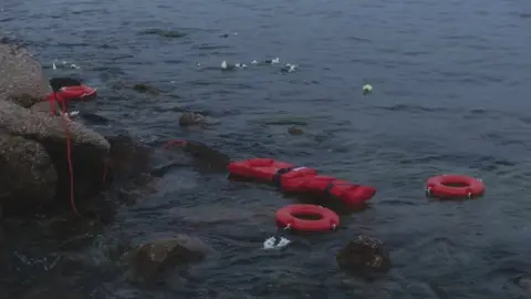 Getty Images Flotation devices are seen floating in the sea as part of a symbolic demonstration for refugee rights by Greek activists on June 20, 2023