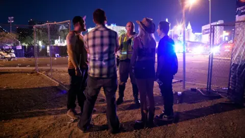 Getty Images four people in festival clothes talking to a man in high vis
