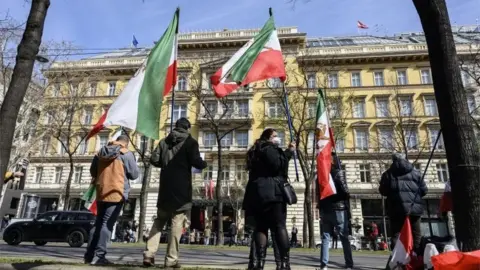 EPA Supporters of an Iranian opposition group wave flags outside hotel where talks are taking place in Vienna (09/04/21)