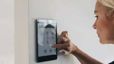 Getty Images Woman adjusting thermostat