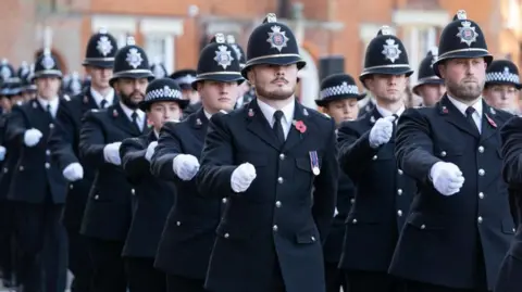 Essex Police Police officers wearing black jackets, hats and white shirts marching in front of Essex Police HQ in Chelmsford.