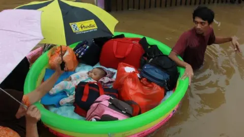 Antara Foto/Muhammad Iqbal/ via REUTERS A baby is evacuated by a rescue team
