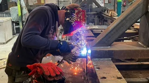 A man with a helmet causing sparks with a machine