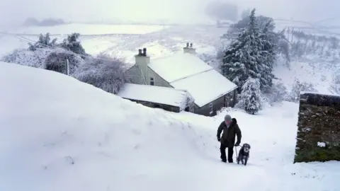 Owen Humphreys/PA Wire A dog walker negotiates heavy overnight snow in Carrshield in the Pennines, near Hexham in Northumberland