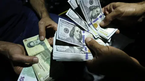 AFP File photo showing a man exchanging Iranian rials for US dollars in Tehran, Iran (8 August 2018)