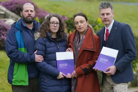 PA Media Colin and Kayleigh Griffiths, Rhiannon Davies and Richard Stanton with a copy of the report