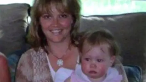 Liv Shelby Lisa and Liv together, Liv is a baby and is sat on Lisa's lap - Lisa is smiling at the camera