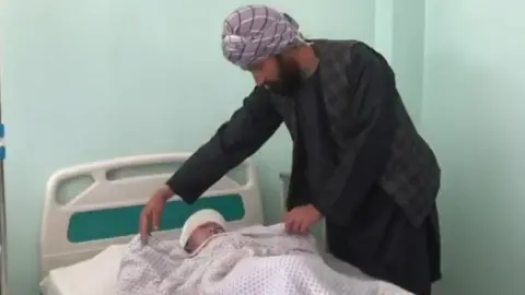 BBC Man with injured child at hospital in Takhar, Afghanistan, on 22 October 2020
