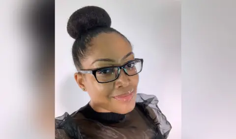 Dee Moore A woman wearing glasses smiling at the camera