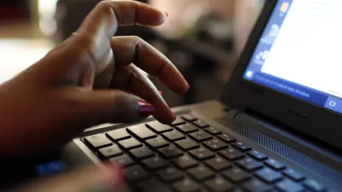 Getty Images A hand typing on a laptop