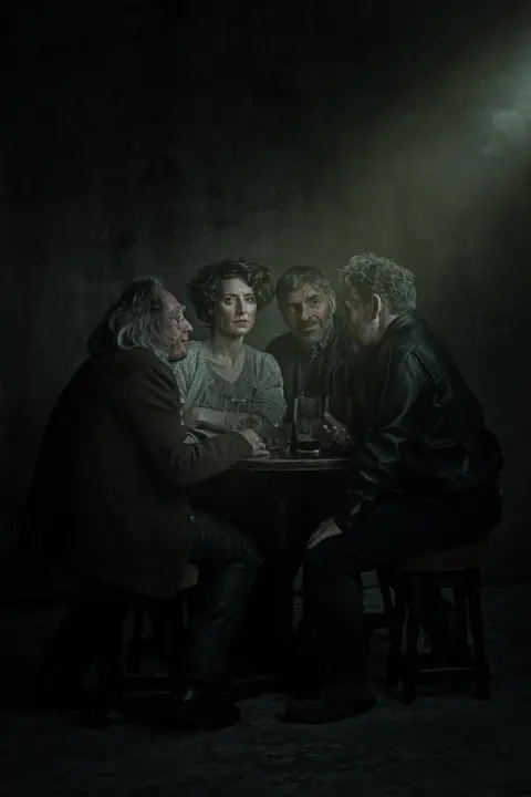 Michael Wharley A group of people sat around a small table in the dark