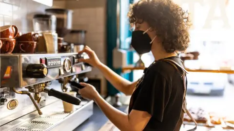 Mary Evans Picture Library Barista wearing face mask makes a coffee