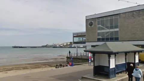 Google Mowlem Theatre building in Swanage with the sea and the pier in the background