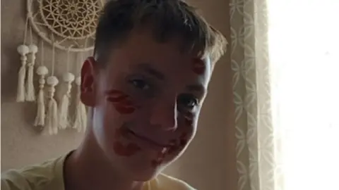 Family handout Tomasz with red paint and lipstick marks on his face