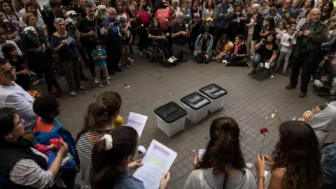 Getty Images People stand around ballot boxes during a tribute outside a school which acted as polling station in the referendum and was subsequently raided, during a regional general strike to protest against the violence that marred Sunday's referendum vote (03 October 2017)