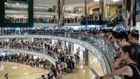 Getty Images Residents and protesters sing songs and shout slogans as they gather at a shopping mall after business hours in Tai Koo district