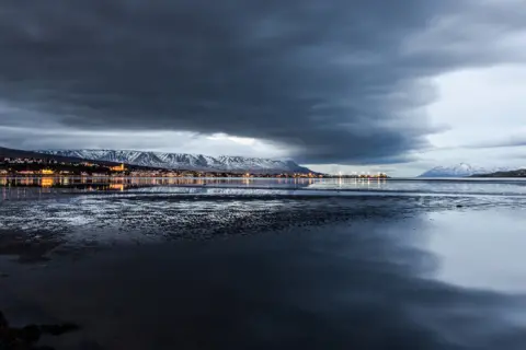 Berglind H Helgadóttir Clouds reflected over water with snow-capped mountains in the distance
