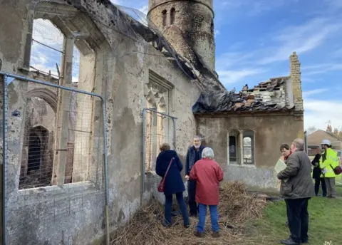 Jill Bennett/BBC Villagers looking inside the church